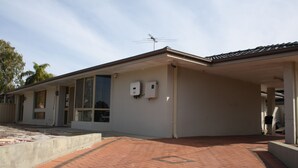 A building with a flat roof, a covered entrance, and a brick pathway leading to the entrance. - cozy room (morley)