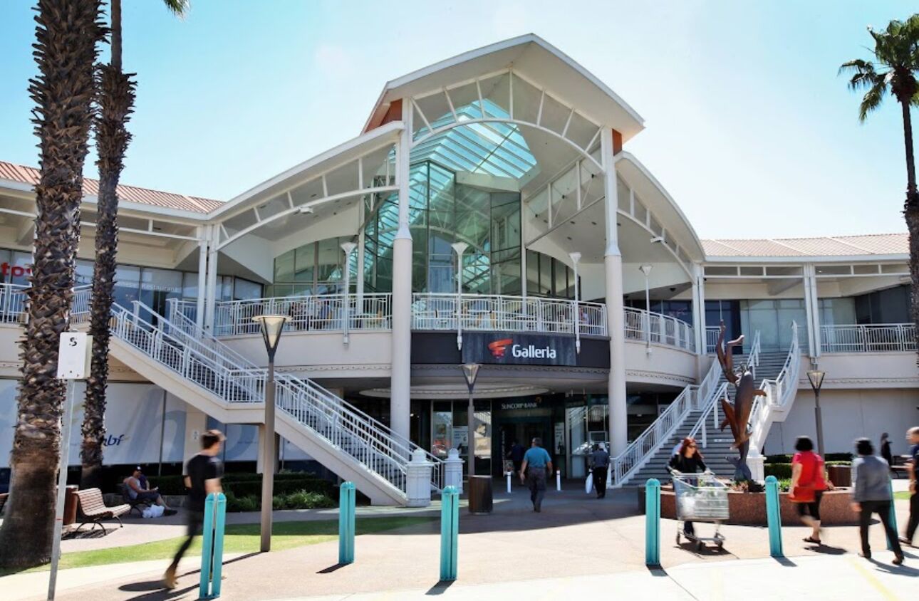 A modern building with a glass facade, a staircase, and a sign that reads 'Galeria.'