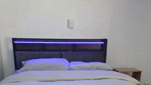 A bed with a patterned headboard, a bedside table, and a wall switch. - cozy room (morley)