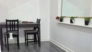 A room with a dining table and chairs, a window with a mirror, and a shelf with potted plants. - cozy room (morley)