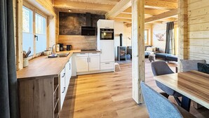 A wooden cabin interior with a kitchen, dining area, and a fireplace.