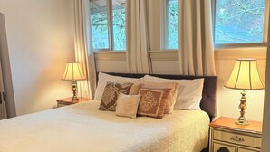 A bedroom with a large bed, two bedside lamps, a ceiling fan, and windows with curtains. - University House  3-bedroom with AC in charming Eugene (Eugene)