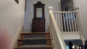 A staircase with carpeted steps, a wooden dresser, a mirror, and a chandelier. - University House  3-bedroom with AC in charming Eugene (Eugene)