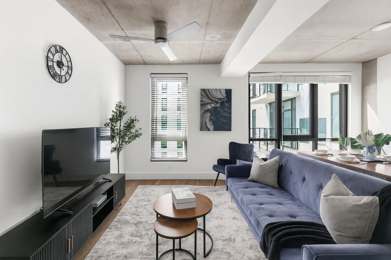 Un salon moderne avec un canapé, un téléviseur et un ventilateur de plafond.