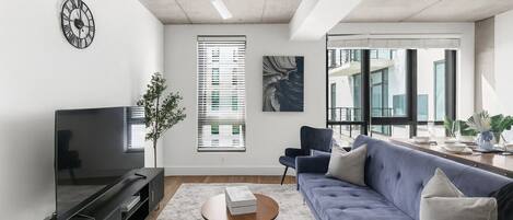 Un salon moderne avec un canapé, un téléviseur et un ventilateur de plafond.