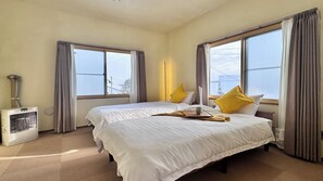 Ein Hotelzimmer mit zwei Betten, einem Heizkörper und großen Fenstern mit Vorhängen.