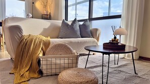 Ein modernes Wohnzimmer mit einer Couch, Kissen, einer Lampe und einem kleinen Tisch.