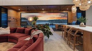 A modern living room with a large painting, a pool, wooden furniture, and a bar area. - Dazzling Design Meets Spectacular Views (Eatonton)