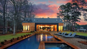 A modern house with a swimming pool, outdoor seating, and a view of the sky. - Dazzling Design Meets Spectacular Views (Eatonton)
