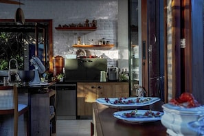 Una cocina moderna con armarios de madera, horno empotrado y comedor con mesa para dos.