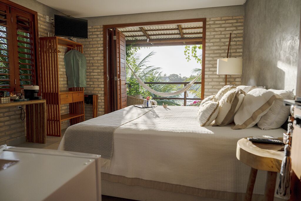 Un dormitorio con cama, televisión, hamaca y vistas al exterior.