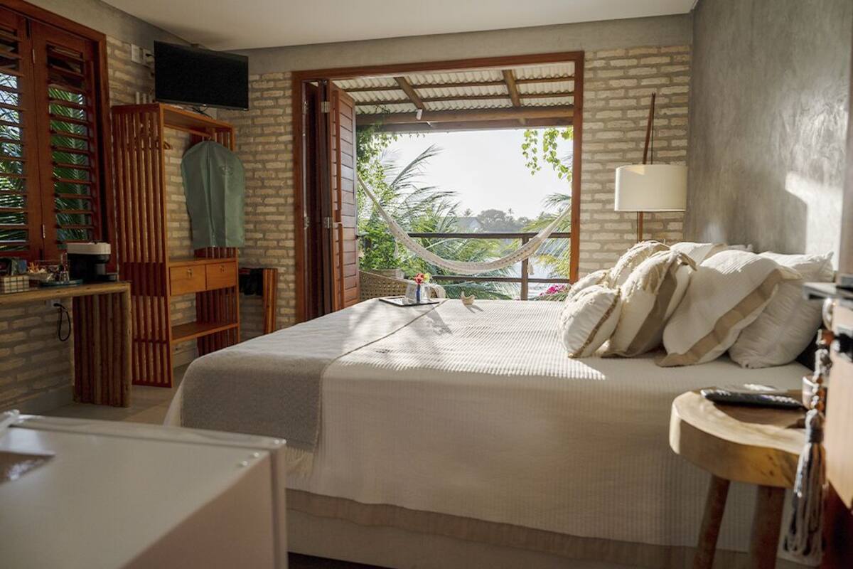 Un dormitorio con cama, televisión, hamaca y vistas al exterior.