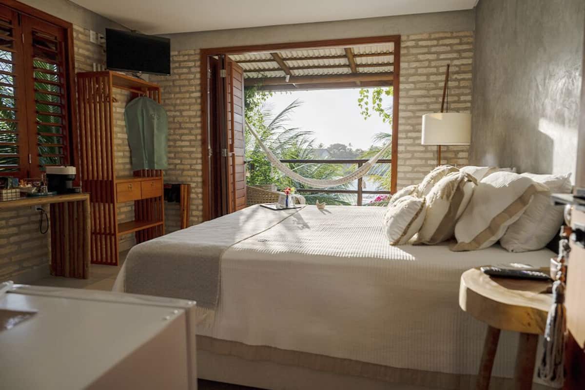 Un dormitorio con cama, televisión, hamaca y vistas al exterior.