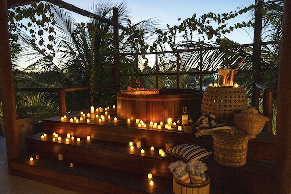 Una terraza de madera con velas, una cesta tejida y un banco.