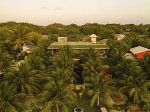 A tropical resort with a central building surrounded by palm trees, a small pool, and a hammock. - Hotel Boutique Quinta Três Marias (Paracuru)