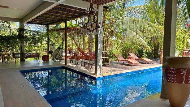 A pool area with a clear blue pool, wooden deck, and lounge chairs. - Hotel Boutique Quinta Três Marias (Paracuru)