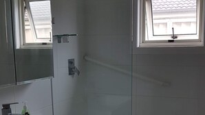 A bathroom with a white vanity, a shower, and a window. - Coastal Grevillea Studio Retreat ,a place to relax or enjoy the outdoors (Ettalong Beach)