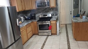 A kitchen with wooden cabinets, a stainless steel refrigerator, a microwave, a stove, and an oven. - Bright & Quiet 2 Bd Nest / 1st FL Getaway (Chicago)