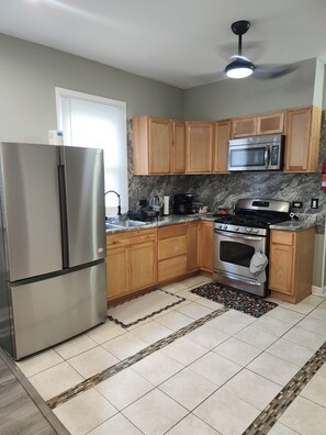 A kitchen with wooden cabinets, a stainless steel refrigerator, a microwave, a stove, and a ceiling fan. - Bright & Quiet 2 Bd Nest / 1st FL Getaway (Chicago)