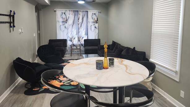 A dining area with a round table, black chairs, a chandelier, and a window with blinds. - Bright & Quiet 2 Bd Nest / 1st FL Getaway (Chicago)