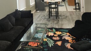 A living room with a glass coffee table, a sofa, and a dining area with a table and chairs. - Bright & Quiet 2 Bd Nest / 1st FL Getaway (Chicago)
