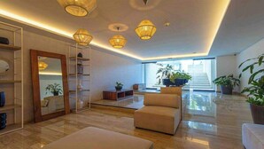 A spacious living area with a high ceiling, multiple seating options, and a staircase leading to an upper level. - Cancun 2BR: Resort Pool, Padel & Playground (Cancún)