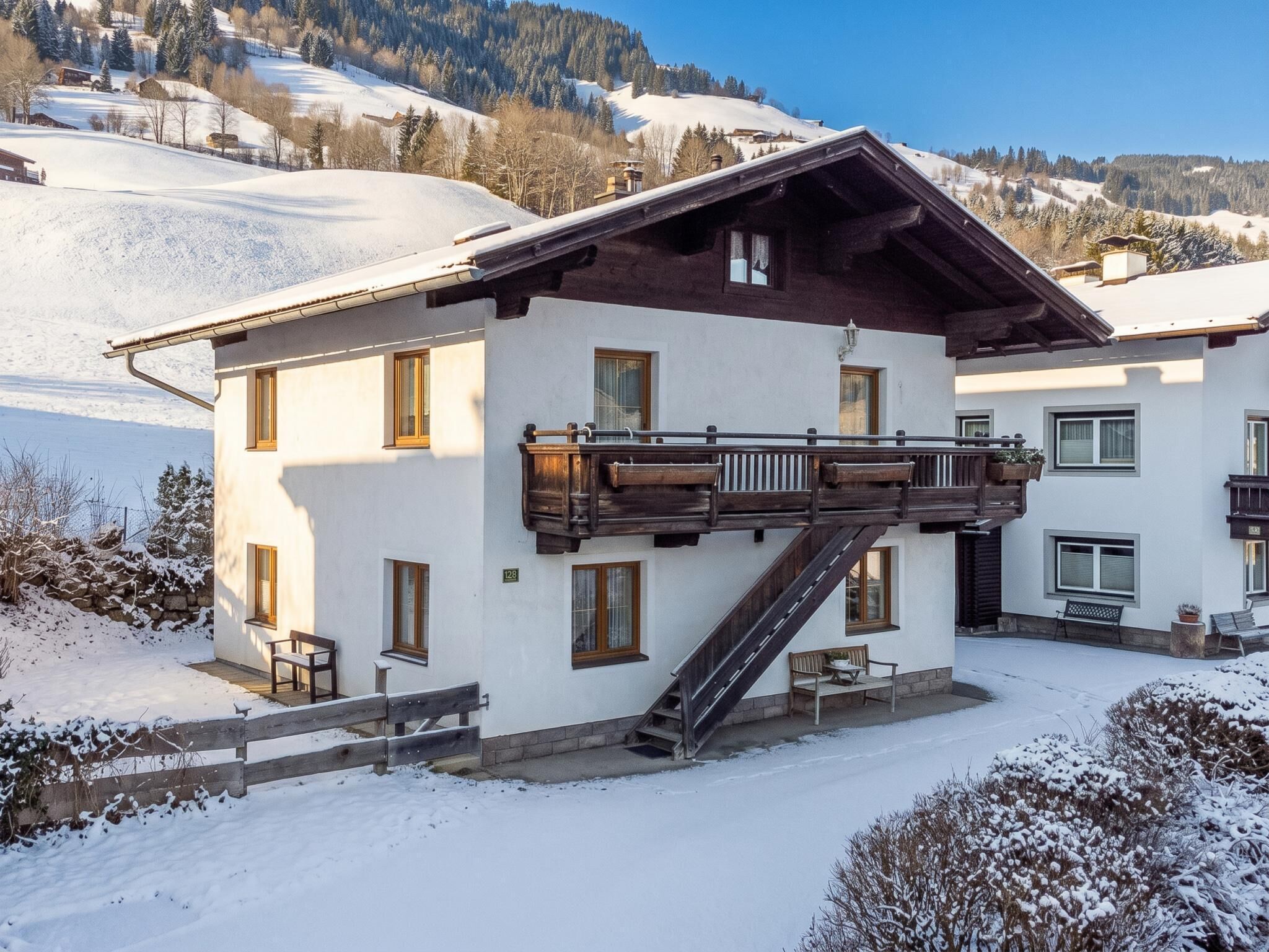 Ein zweistöckiges Gebäude mit einem hölzernen Balkon, einer Treppe und Blick auf eine verschneite Landschaft.