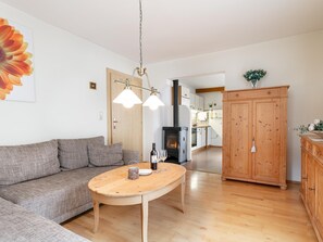 Ein Wohnzimmer mit einer Couch, einem Holztisch, einem Kamin und einer Küche im Hintergrund.