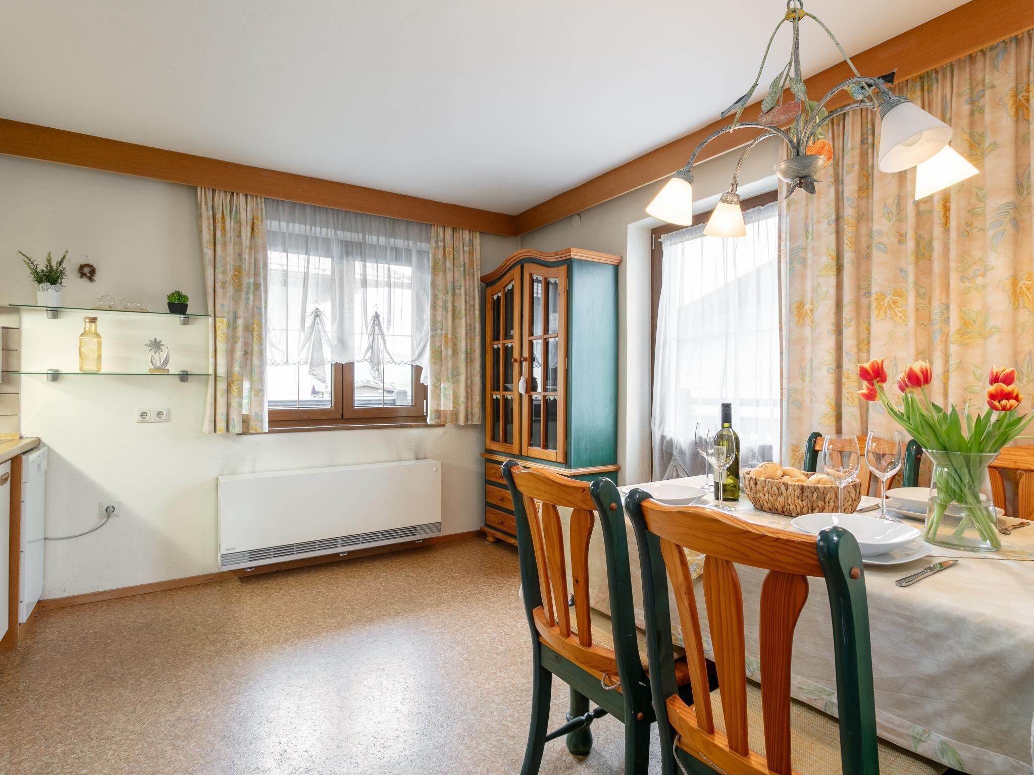 Un comedor con una mesa preparada para dos personas, un armario y un radiador.