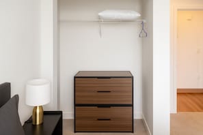 A bedroom with a bed, bedside table, lamp, and a wooden dresser with drawers. - Five Points South | Spacious 2BR w/ 2 Queens D5 (Birmingham)