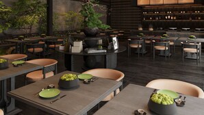 A modern restaurant interior with round tables, chairs, and a bar area.