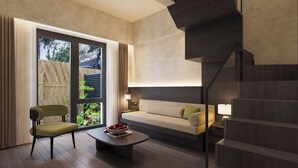 A modern living room with a sofa, a chair, a coffee table, and a staircase.