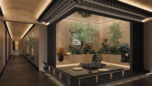A modern interior with a long corridor, a central seating area with a table and chairs, and a wall-mounted planter with greenery.