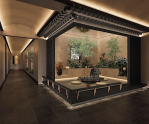 A modern interior with a long corridor, a central seating area with a table and chairs, and a wall-mounted planter with greenery. - Happy Dragon Imperial Garden Courtyard (Beijing)