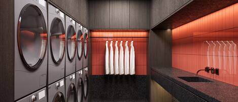 A laundry area with multiple washing machines, a sink, and a towel rack.