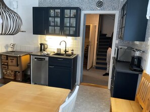 A compact kitchen with a sink, cabinets, and a dining area with a table.