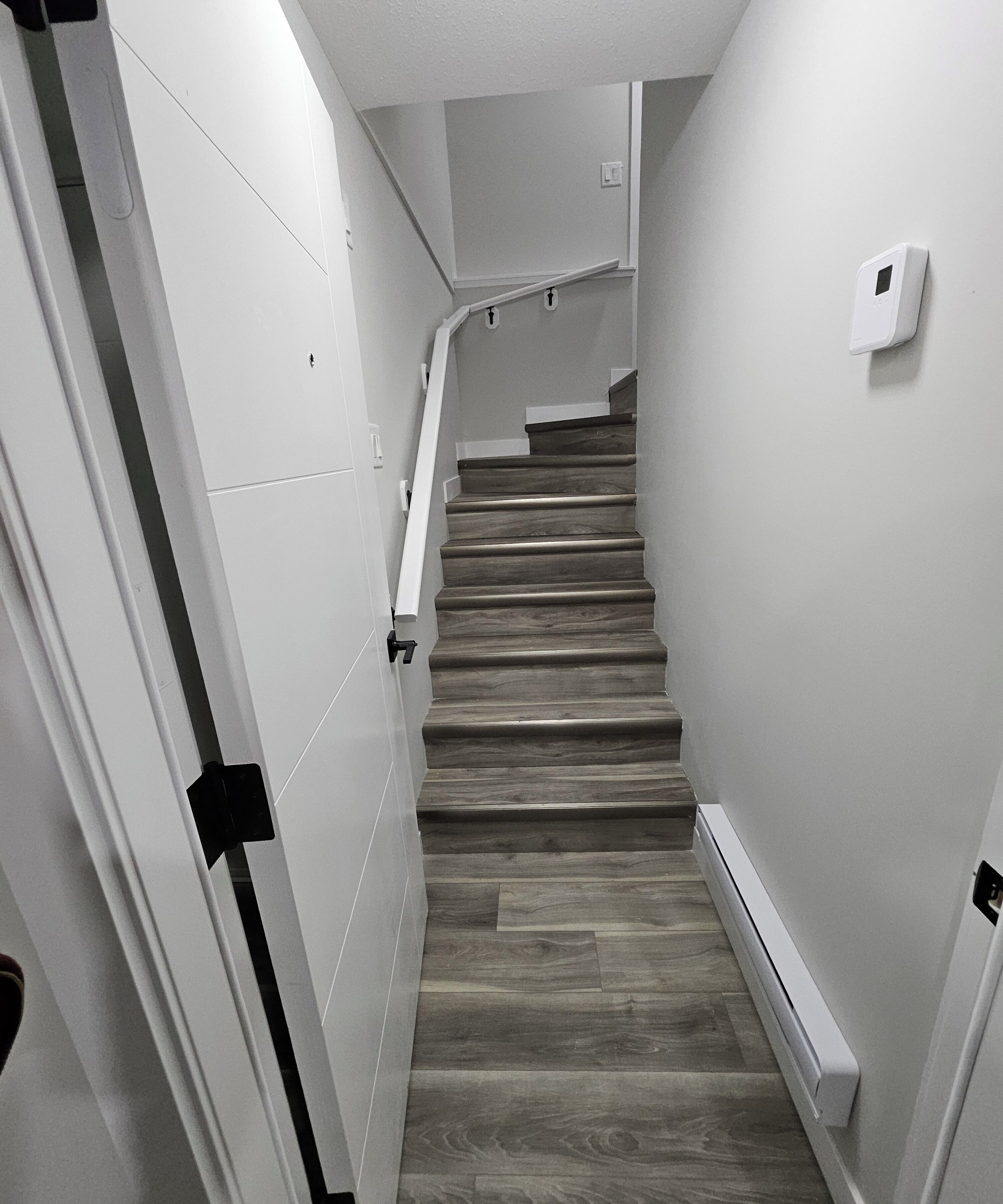 A staircase with wooden steps and white walls, leading to an upper floor.