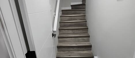 A staircase with wooden steps and white walls, leading to an upper floor.