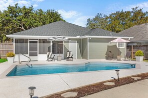 A house with a swimming pool, a covered patio with chairs, and a fenced backyard. - Sunny Daze - 3BDR with Pool (Orange Beach)