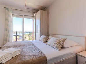 A hotel room with a bed, a nightstand, a window with curtains, and a balcony view. - Villa Mare by Interhome (Rab/Lopar)