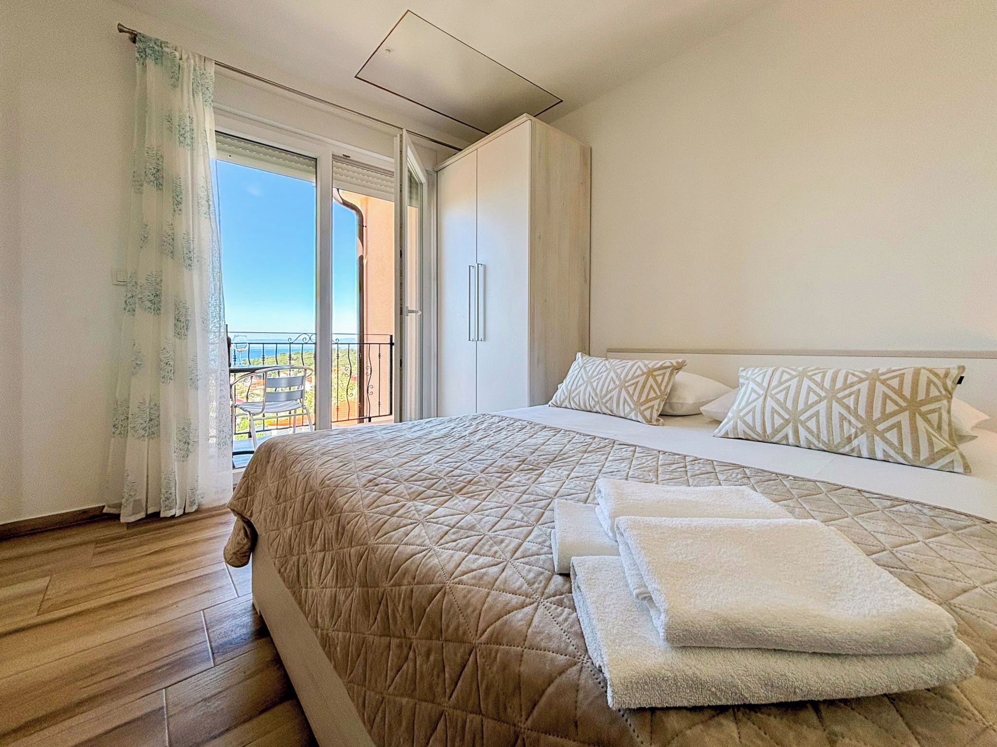 Une chambre à coucher avec un lit, des oreillers, une vue sur l’extérieur et un balcon.