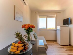 A dining area with a table set for two, a fruit bowl, a vase with flowers, and a view of the outdoors through a window. - Villa Mare by Interhome (Rab/Lopar)