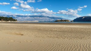 Een strand met een heldere lucht en bergen op de achtergrond.