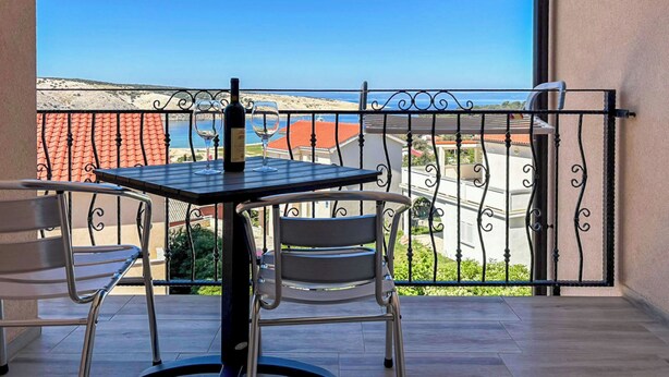 Ein Balkon mit Tisch, Stühlen und einer Weinflasche.