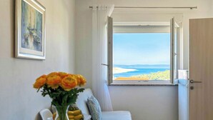 Ein Zimmer mit Blick auf den Strand, ein Sofa, ein Tisch mit Blumenvase und eine Tür.