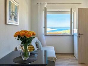 Ein Zimmer mit Blick auf den Strand, ein Sofa, ein Tisch mit Blumenvase und eine Tür.