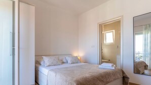 Ein Schlafzimmer mit einem Bett, einem Nachttisch, einem Spiegel und einer Tür, die auf einen Balkon führt.