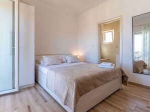 Ein Schlafzimmer mit einem Bett, einem Nachttisch, einem Spiegel und einer Tür, die auf einen Balkon führt.