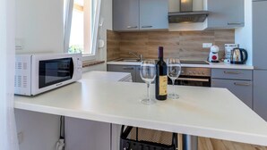 Eine moderne Küche mit Mikrowelle, Weingläsern, einer Weinflasche, einer Kaffeemaschine und einem Wasserkocher.