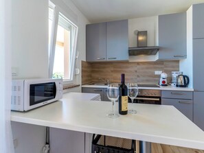 Eine moderne Küche mit Mikrowelle, Weingläsern, einer Weinflasche, einer Kaffeemaschine und einem Wasserkocher.
